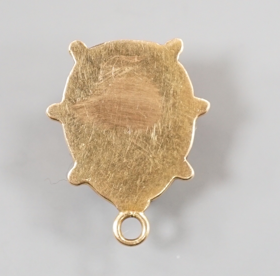 A modern yellow metal and two colour enamel set ladybird pendant, overall 19mm, gross weight 1.7 grams.